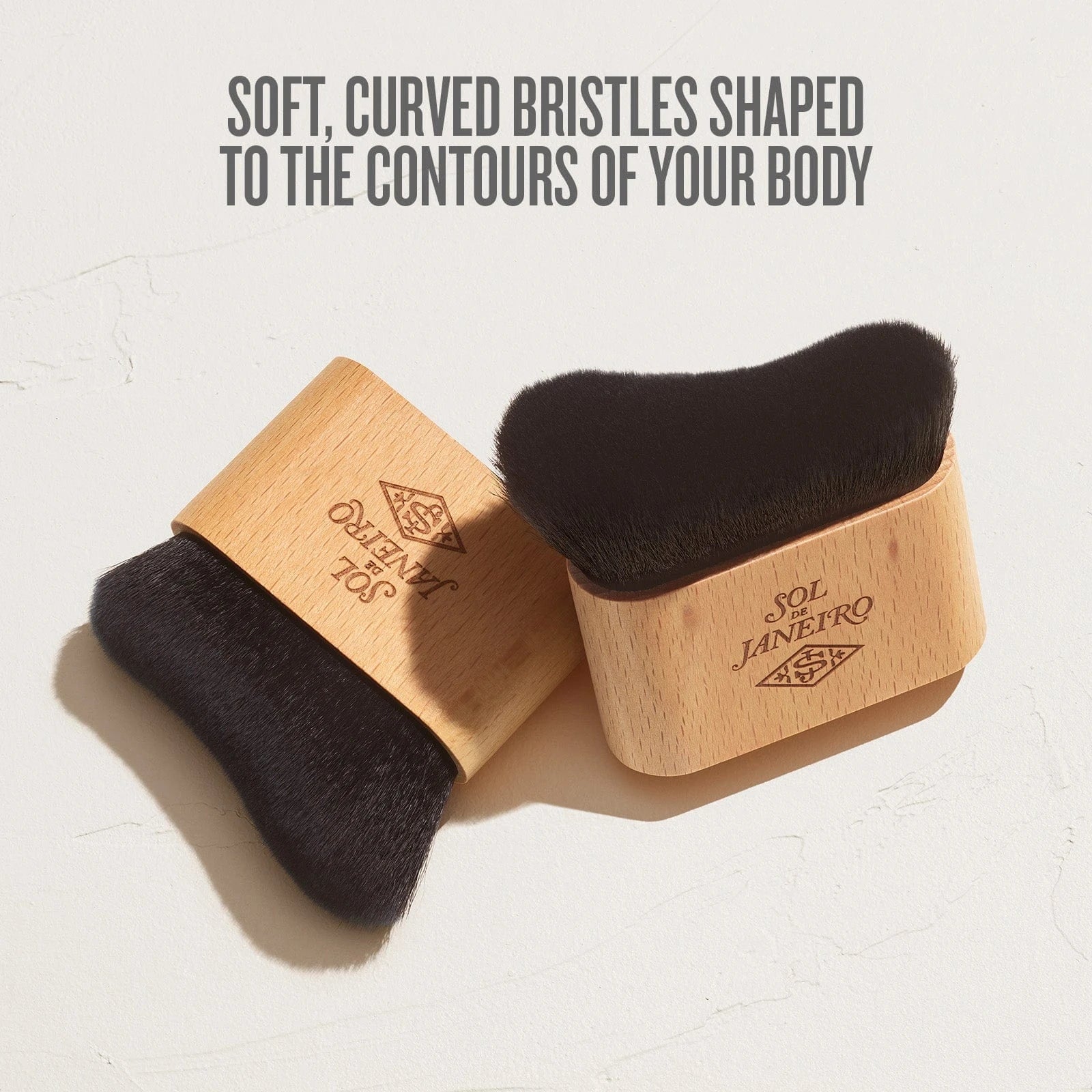 the text on image reads soft, curved bristles shaped to the contours of your body. This image is showing an up close show of the glowmotions brush