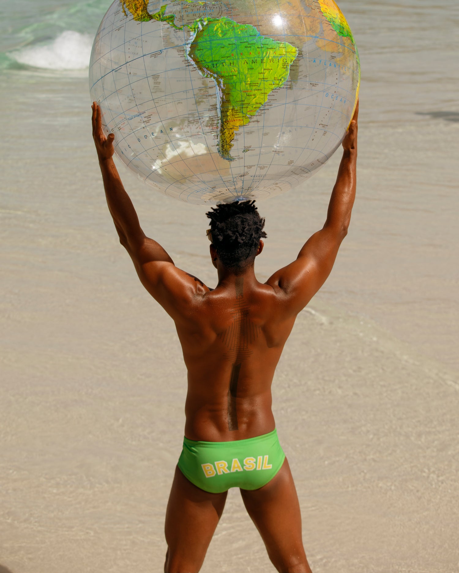 man on beach holding a globe beach ball over his head