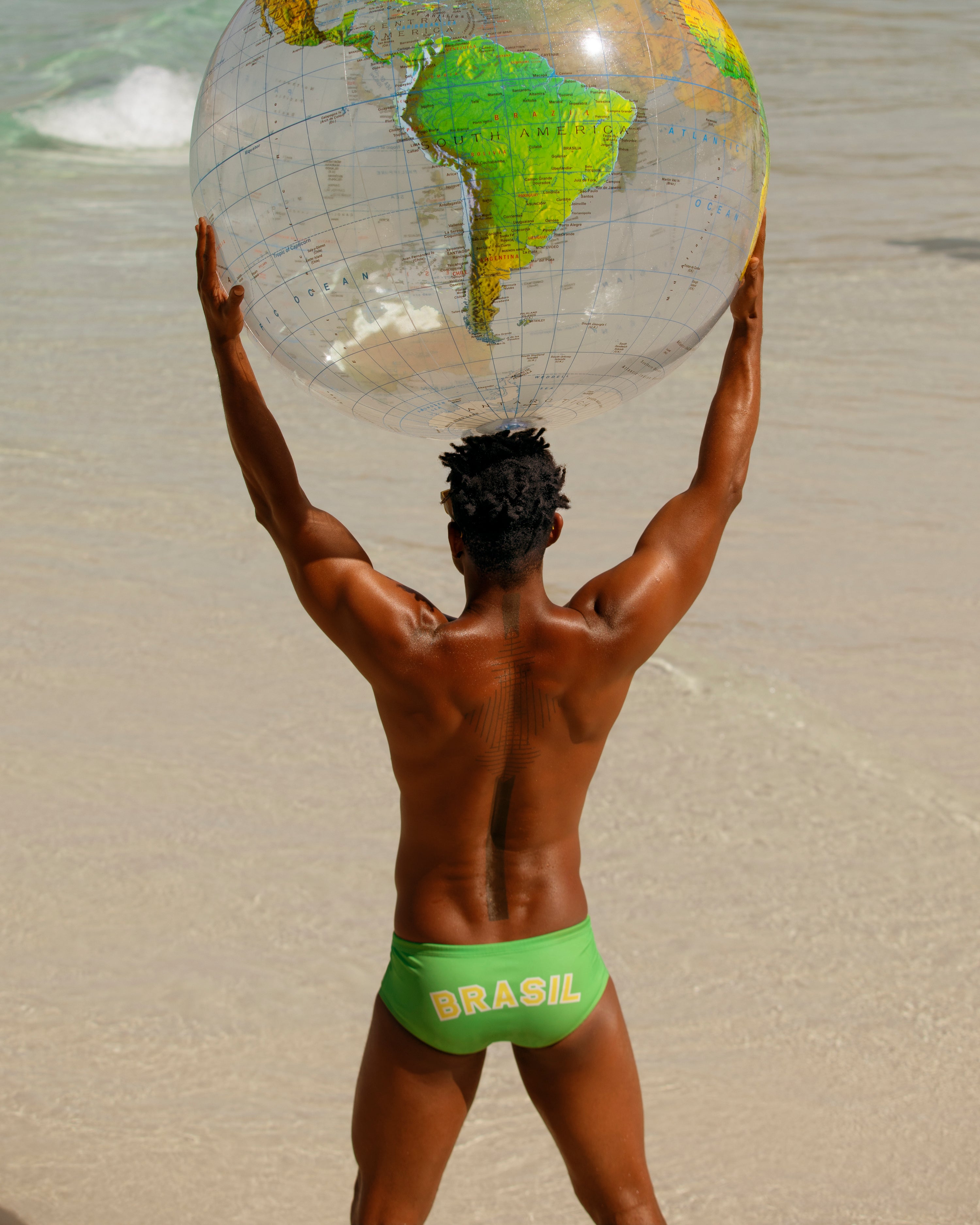 man on beach holding a globe beach ball over his head