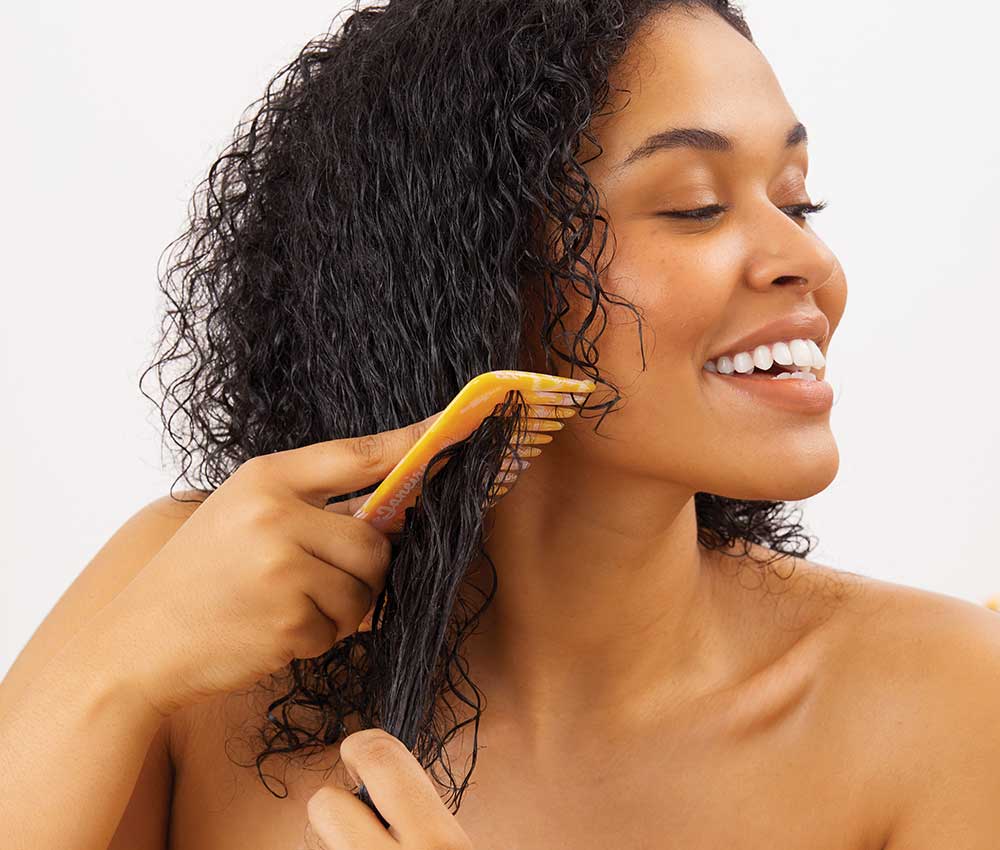 Model combing through hair using Sol de Janeiro comb