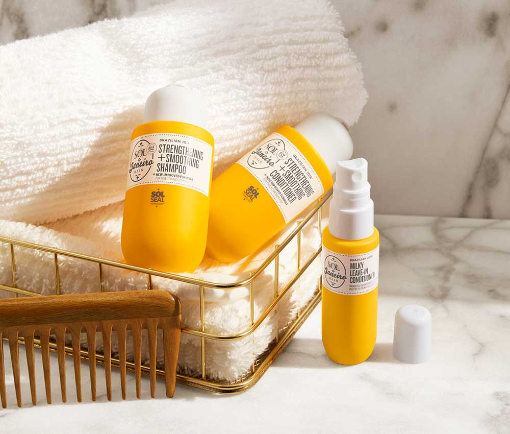 Joia Strengthening shampoo & conditioner, milky leave in conditioner. Products placed in towel basket on marble counter next to Sol de Janeiro comb.