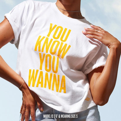Front shot of the badalada t-shirt that reads &quot;you know you wanna&quot; in sol de janeiro yellow. T shirt is white